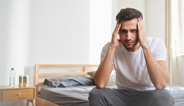 Мужчина сидит и держится за виски